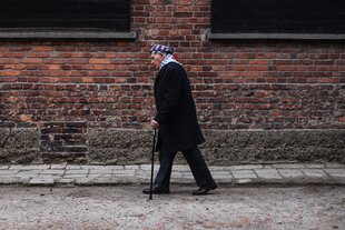 Zalewski mit Gehstock vor den Mauern von Auschwitz