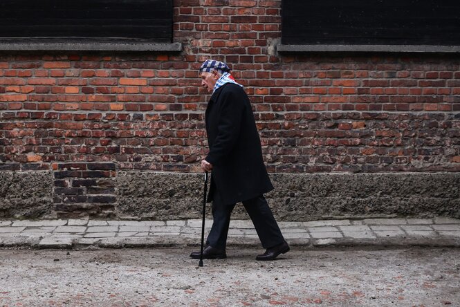 Zalewski mit Gehstock vor den Mauern von Auschwitz