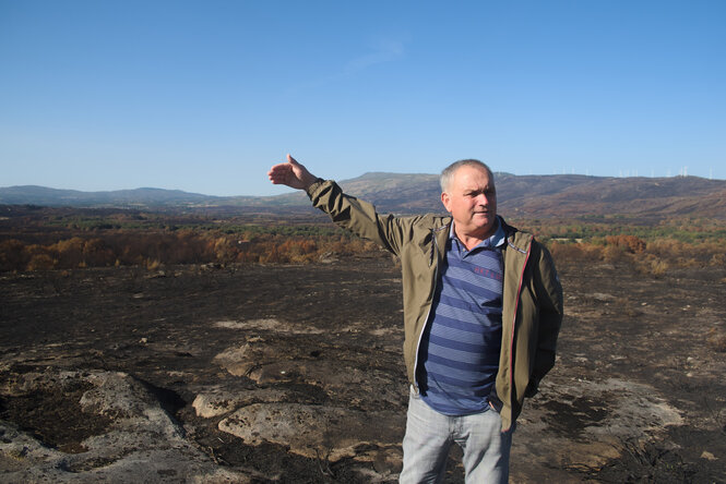 David Dominguez steht in einer verkohlten Landschaft und zeigt in die Ferne