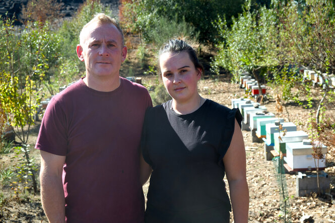Sindo Justo und Noelia González stehen zusammen vor ihren Bienenstöcken