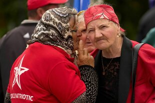 Frauen mit Kopftüchern und roten T-Shirts flüstern auf einer Kundgebung miteinander