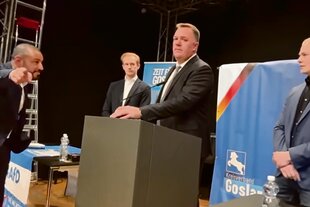 Man sieht vier Personen sich anschreien auf einer Bühne vor dem Banner der AfD Goslar