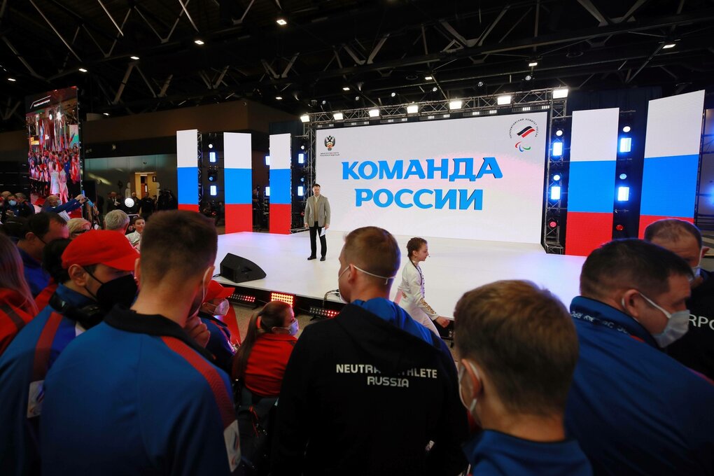 Eine Bühne mit projizierten russischen Flaggen im Hintergrund, dazu die russische Aufschrift „Team Russland“. Im Vordergrund Athlet:innen