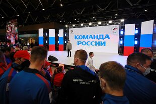 Eine Bühne mit projizierten russischen Flaggen im Hintergrund, dazu die russische Aufschrift „Team Russland“. Im Vordergrund Athlet:innen