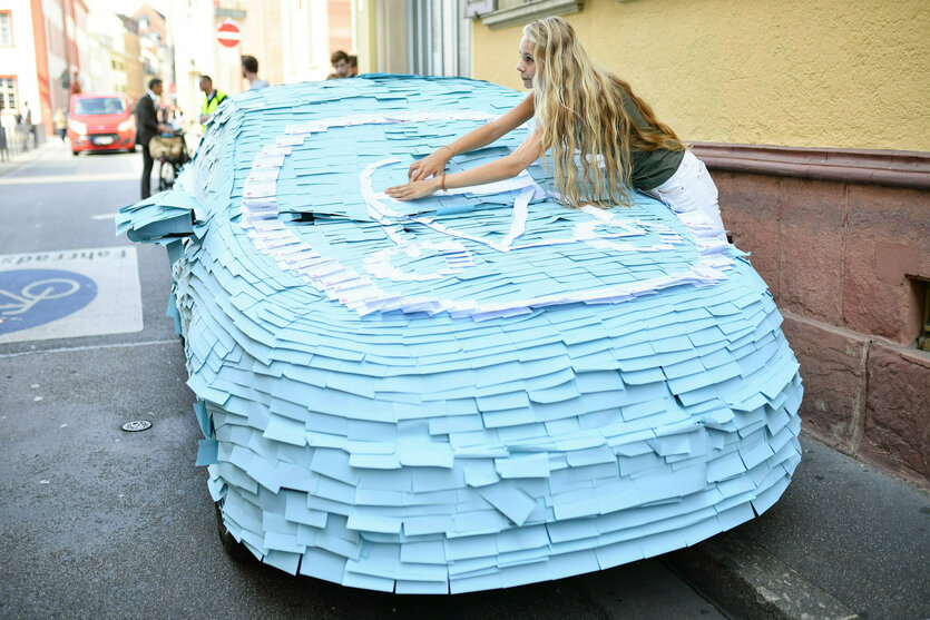 Ein falsch parkendes Auto wird komplett mit Zetteln beklebt