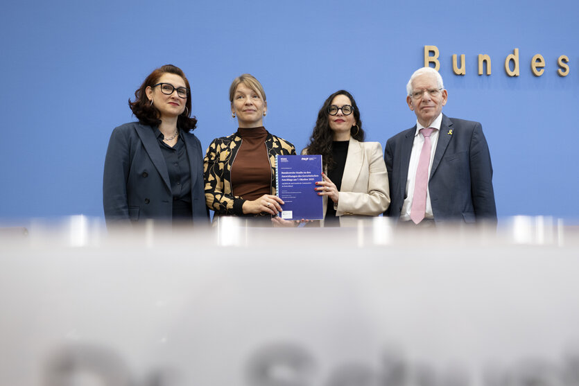 Vor der blauen Wand der Bundespressekonferenz stehen drei Frauen und ein Mann, die beiden Frauen in der Mitte halten die Studie in der Hand