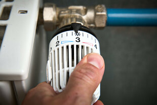 Eine Person dreht an einem Heizungsthermostat