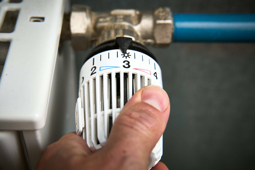 Eine Person dreht an einem Heizungsthermostat