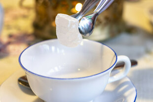 Zucker wird in eine Teetasse gegeben.
