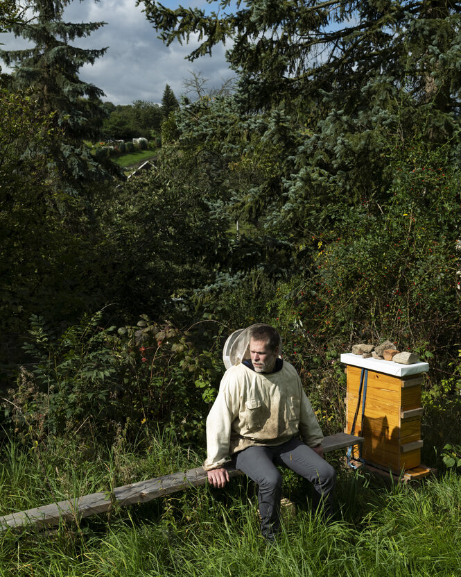 Porträt von Malte Eismann auf einer Wiese mit Bienenstock.