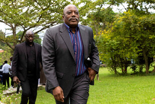 Joseph Kabila im Anzug und Schnauzbart läuft mit anderen Männern durch einen Park
