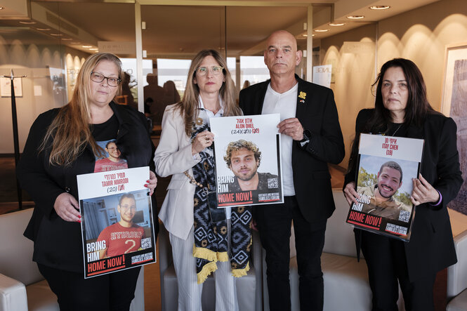 Vier Personen halten Schilder mit Fotos.