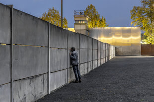Ein Mann schaut durch eine Ritze in der Mauergedenkstätte Bernauer Straße