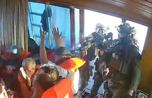 Israelische Soldaten zielen auf Aktivisten in Schwimmwesten, die ihre Hände hoch halten