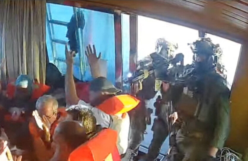 Israelische Soldaten zielen auf Aktivisten in Schwimmwesten, die ihre Hände hoch halten