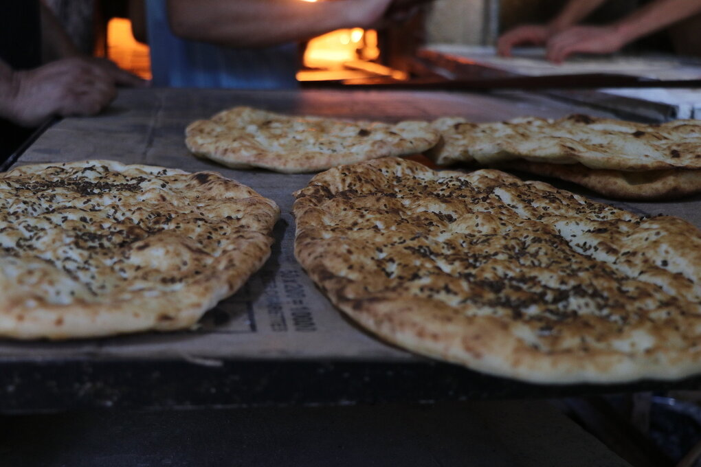 Fladenbrot kommt frisch aus dem Ofen, in dem Flammen lodern