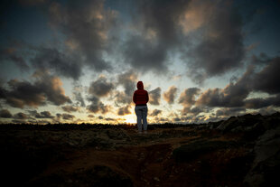 Eine einzelne Person in einer Landschaft mit bedrohlichem Himmel