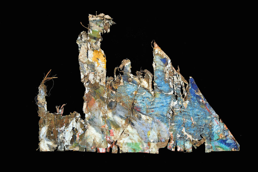 Ein Stück zerrissenes Leinwand mit einem Gemälde darauf in Blau-, Gelb-, Grün- und Brauntönen auf schwarzem Grund