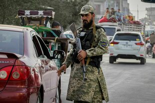 Ein Polizist der Taliban mit einem Gewehr kontrolliert ein Auto