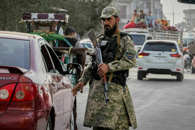 Ein Polizist der Taliban mit einem Gewehr kontrolliert ein Auto