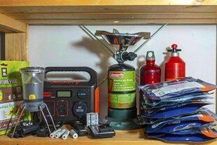 Notfallausrüstung steht im Regal, ein Campingkocher mit Gas-Kartuschen, Tachenlampe, Radio, Batterien