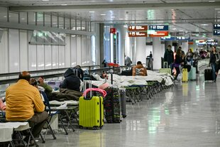 Menschen auf Feldbetten in einer Halle