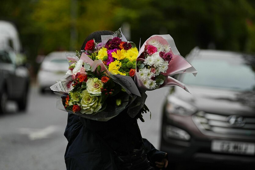 Ein Mensch trägt Blumensträuße auf einer Straße