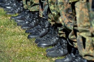 Die Stiefel und und Hosenbeine von Soldaten, die in einer Reihe auf einem Rasen stehen