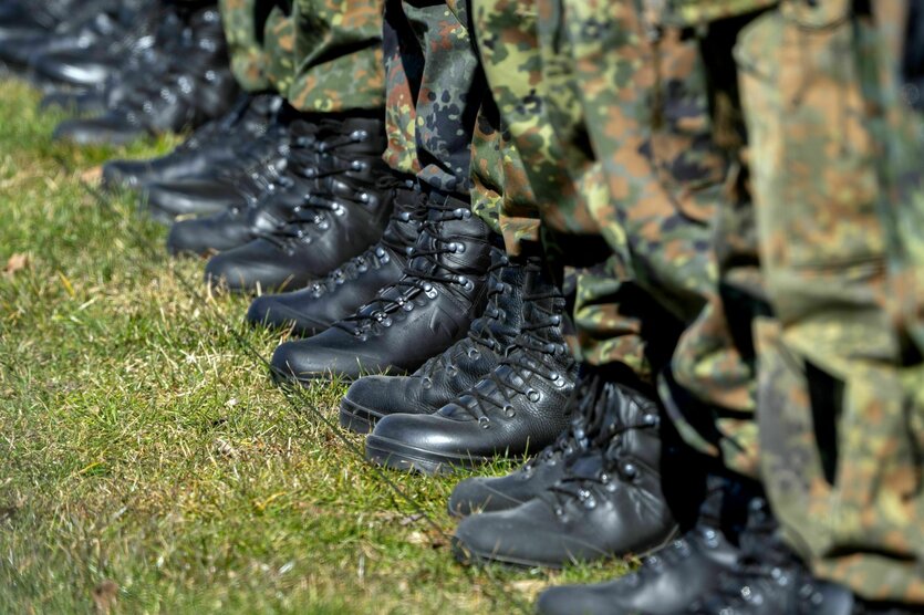 Die Stiefel und und Hosenbeine von Soldaten, die in einer Reihe auf einem Rasen stehen