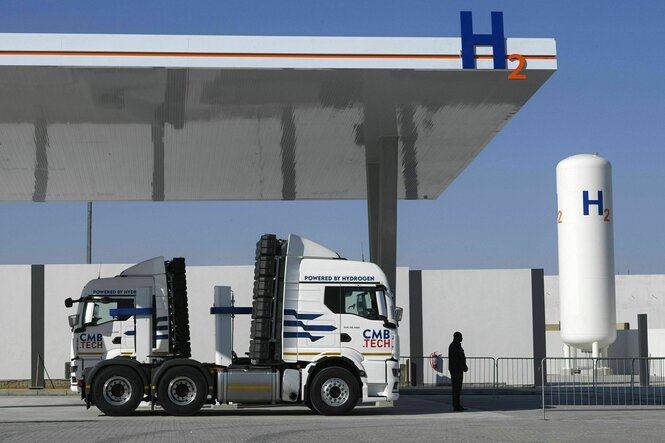 Eine Anlage für grünen Wasserstoff in Namibia - ein LKW steht unter einem Vordach, im Hintergrund ein Speicher mit der Aufschrift H2O