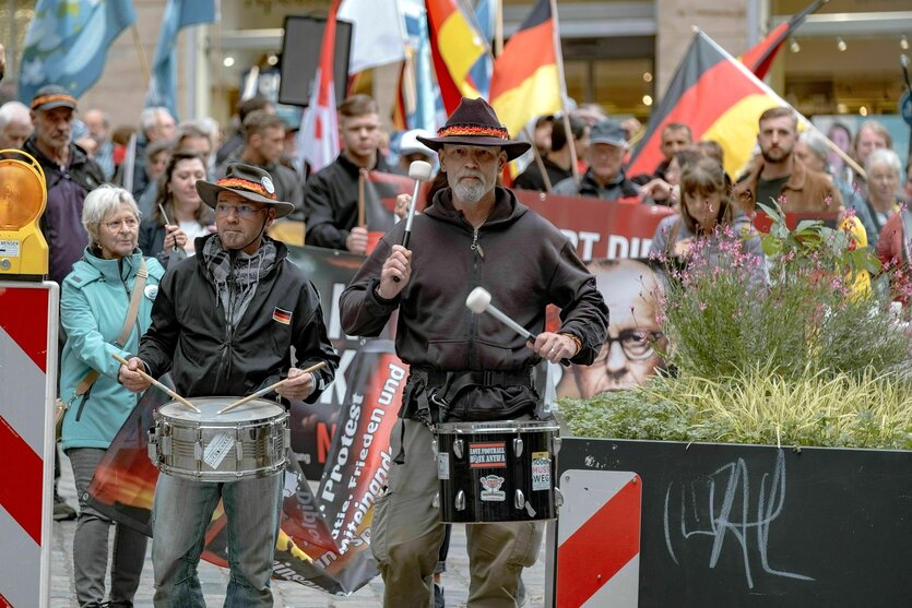 Deutschlandflaggen, Frieidensflaggen werden hoch gehalten, im Vordergrund zwei Trommler mit Hüten