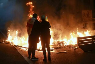 Demonstranten mit einer georgischen und einer ukrainischen Nationalflagge stehen hinter einer brennenden Barrikade unweit einer Polizeiabsperrung