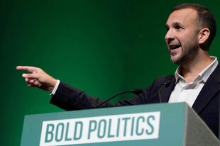 Mann gestikuliert am Rednerpult