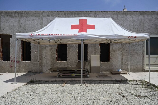 Ein Zelt der Rettungsorganistaion "Rotes Kreuz" vor einer Hausruine