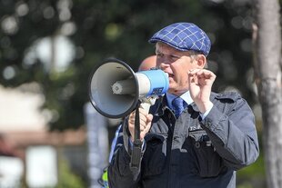 Ein Mann mit karierter Schirmmütze spricht in ein Megafon