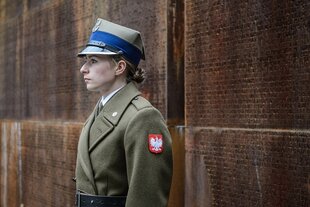 Eine Frau in Uniform steht vor einer Gedenktafel