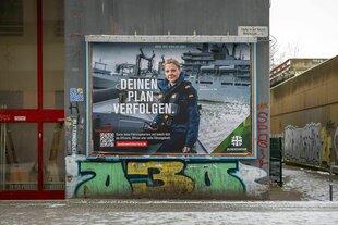 Ein Werbeplakat der Bundeswehr an einer Hauswand mit Graffitis