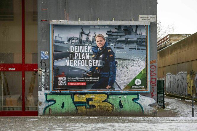 Ein Werbeplakat der Bundeswehr an einer Hauswand mit Graffitis