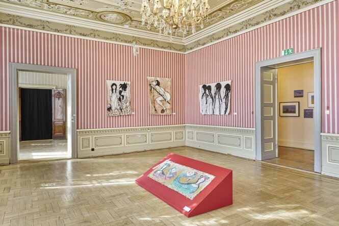 Ein rosa-goldener Raum voller Bilder und Installationen
