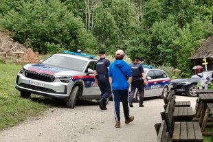 ein Weg mit Menschen und Polizeiwagen