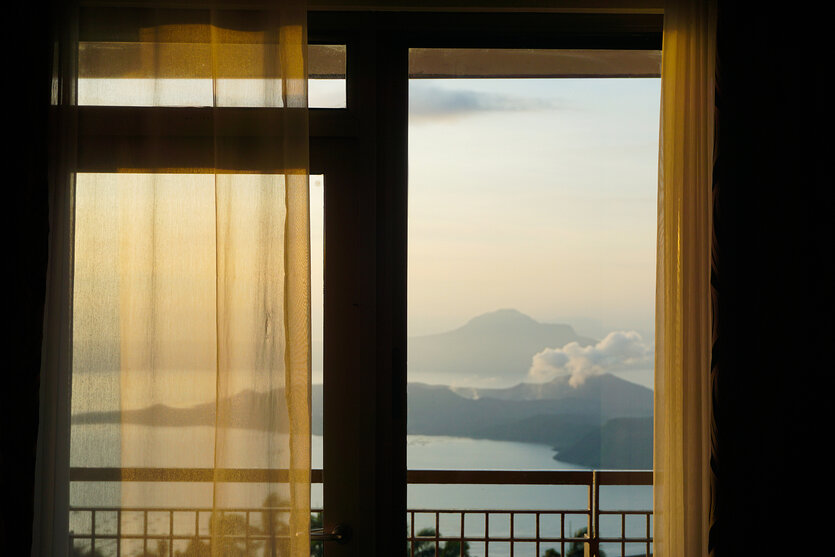 Der Blick aus einem Fenster aufs Meer und einen Vulkan