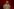 Eine stark geschminkte Frau auf der Bühne vor einem roten Vorhang