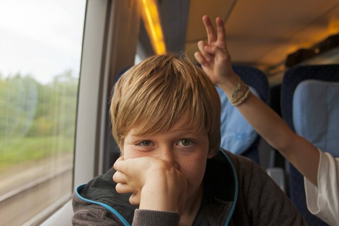 Ein Kind in einem ICE der DEutschen Bahn, ein zweites macht Hasenohren