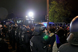 Polizisten und ein Wasserwerfer stehen um eine Demonstration
