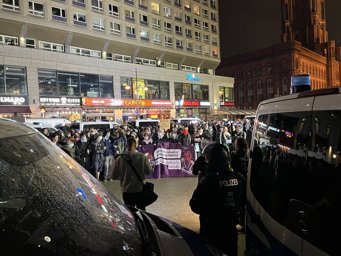 Demonstrant*innen halten ein Transparent, umringt von Polizist*innen