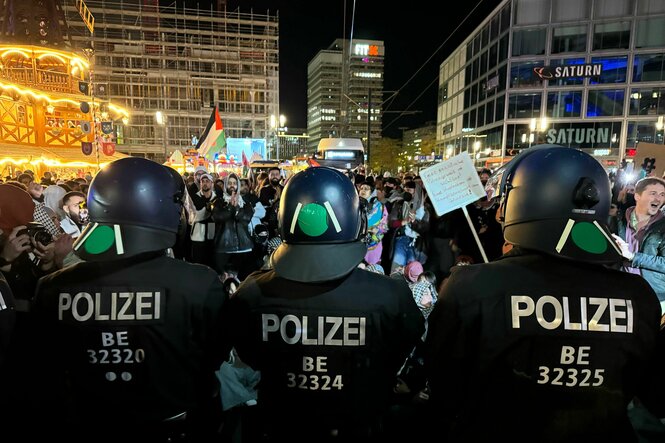 Eine Polizeikette steht vor pro-palästinensischen Demonstranten am Alex