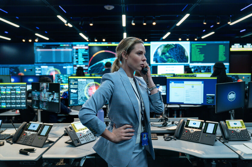 Eine Frau telefoniert vor vielen Bildschirmen