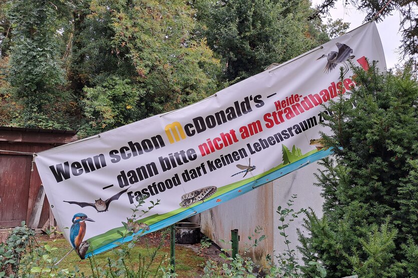 Ein Plakat mit der Aufschrift "Wenn schon McDonalds, dann bitte nicht am Heidebadstrandsee" hängt an einem Wohnhaus in Hemmoor