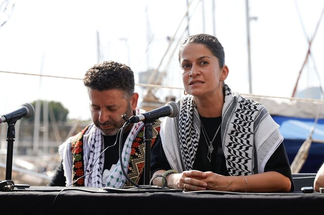 Ein Mann und eine Frau mit Kuffiyahs, die Frau spricht in ein Mikrofon