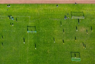Fußballfeld mit Spielern drauf aus der Vogelperspektive fotografiert